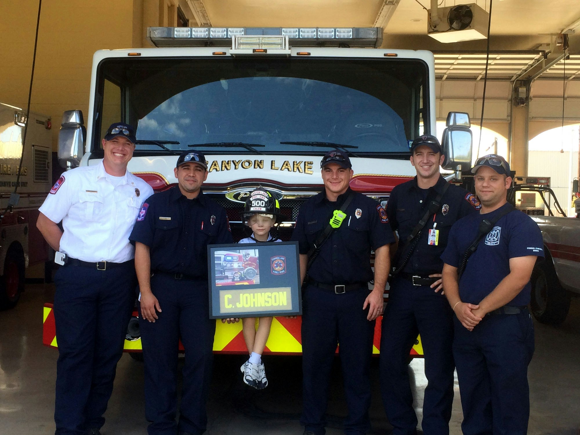 Firefighters with a kid in front of a fire truck.