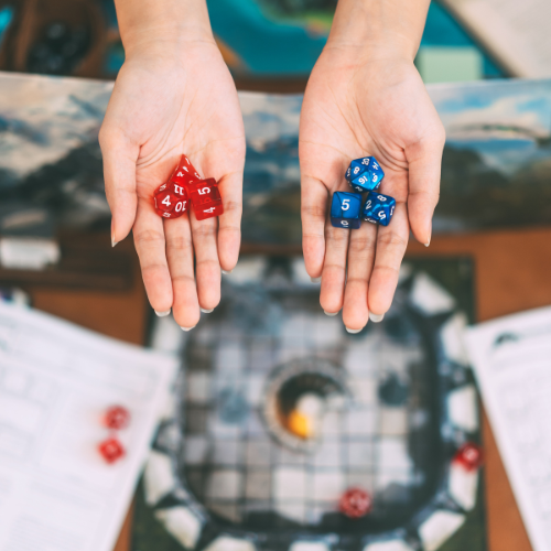 Two hands holding dice: red ones with numbers 4 and 7, blue ones with numbers 5, 5, and 5. Gaming elements are in the background.