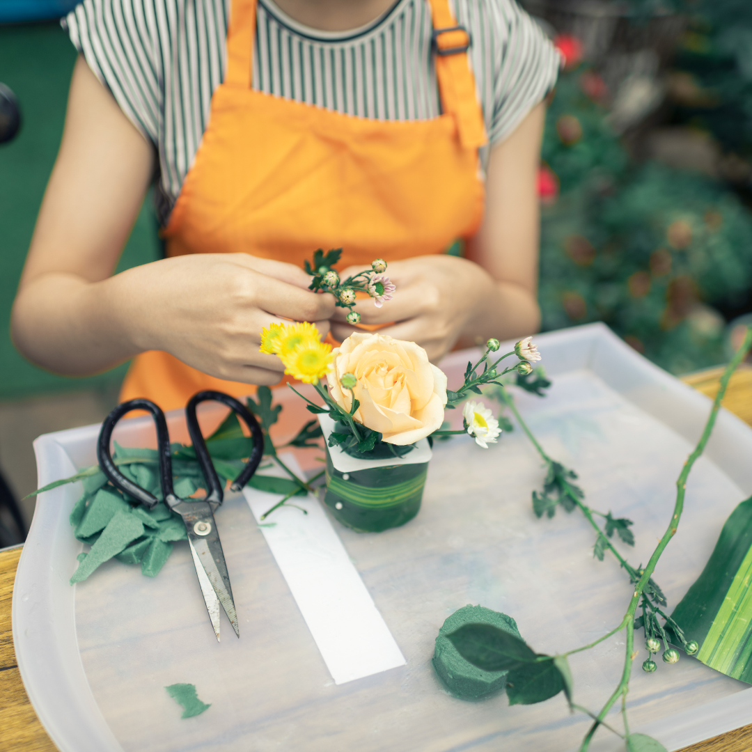 Person arranging flowers with scissors on table.