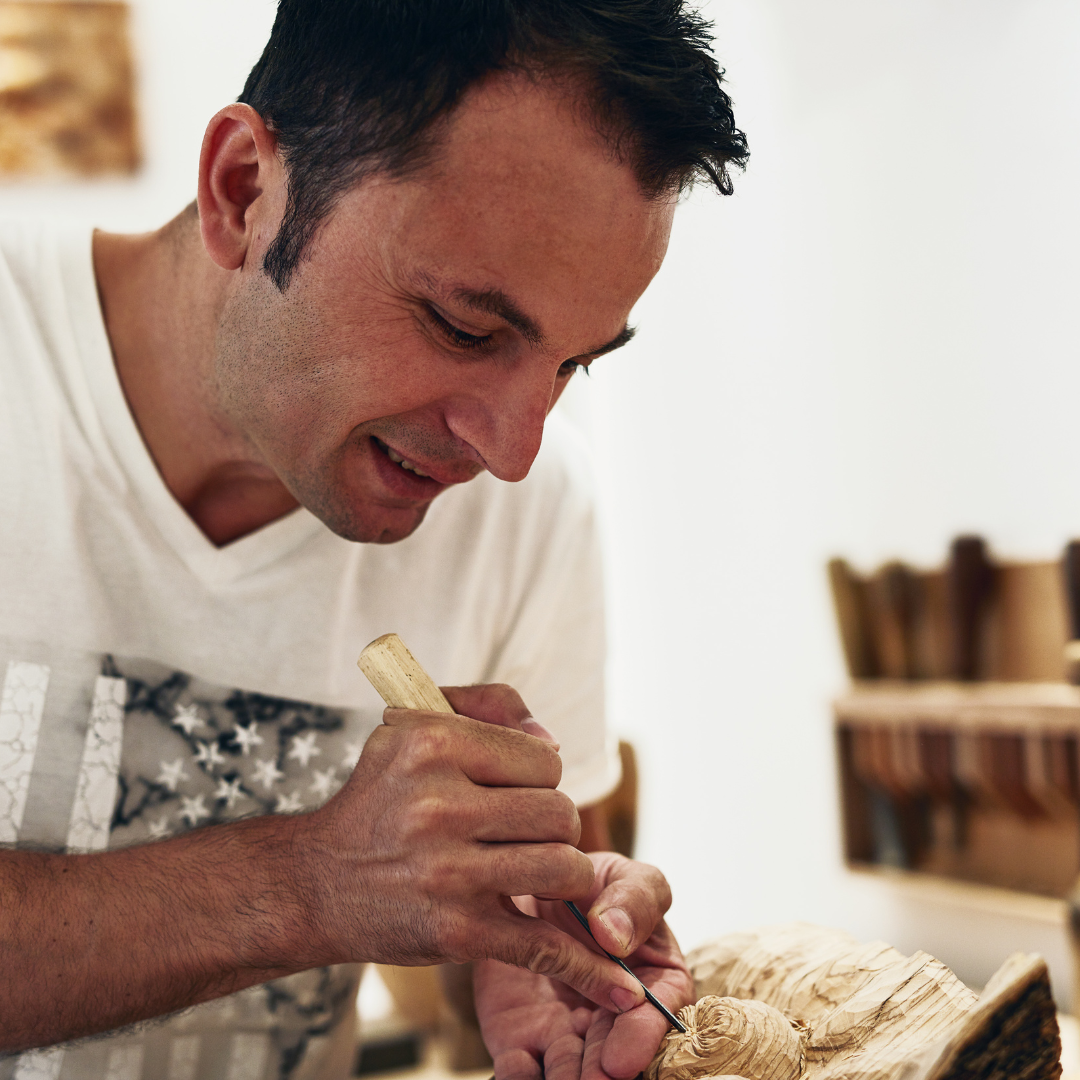 A person carefully carving wood, focused on details.