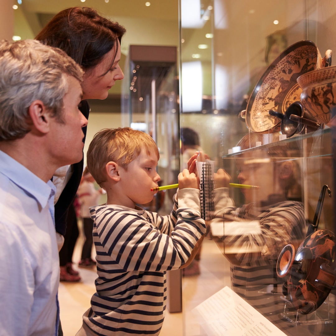 A child and adults examining museum exhibits.