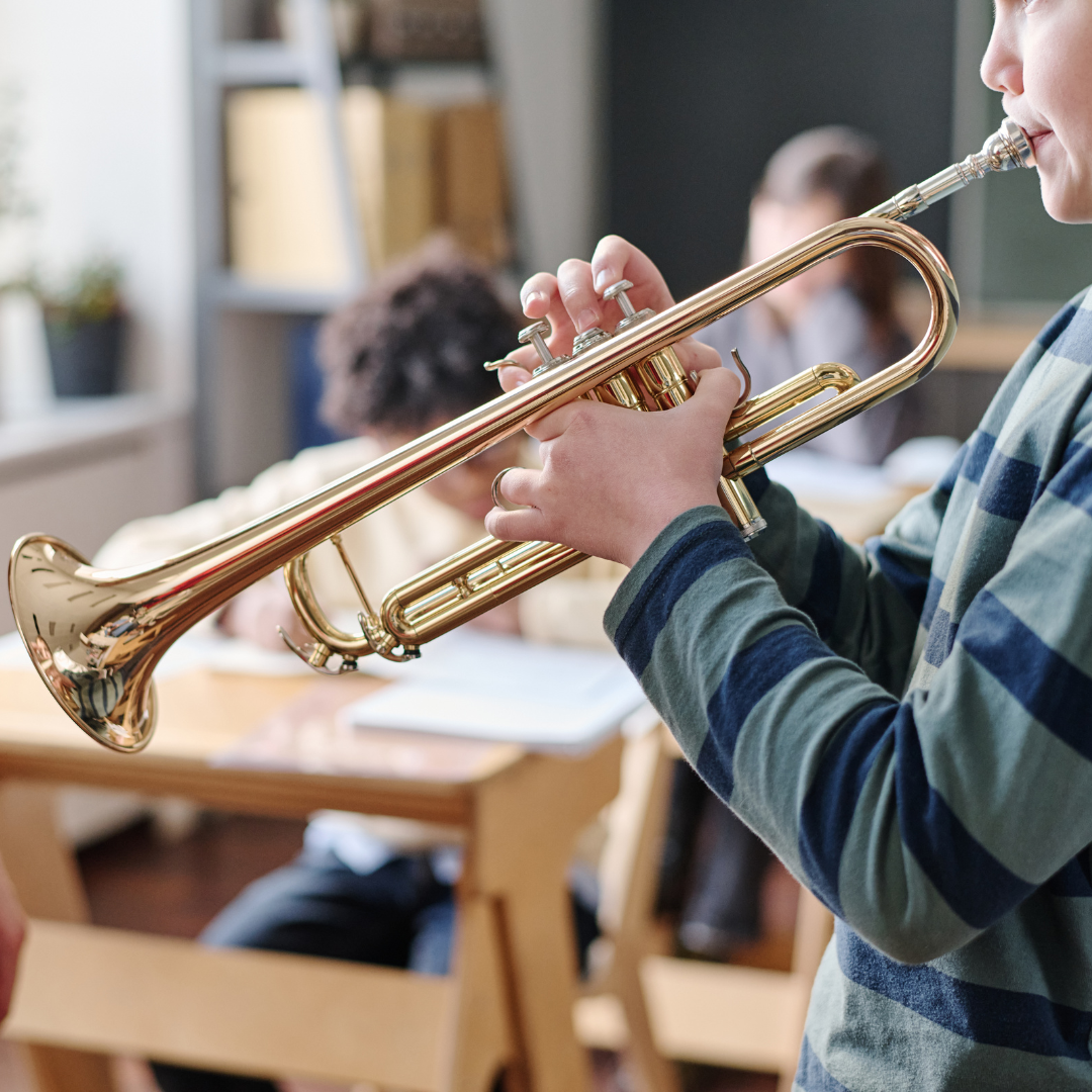A kid playing a trumpet in a classroom setting.