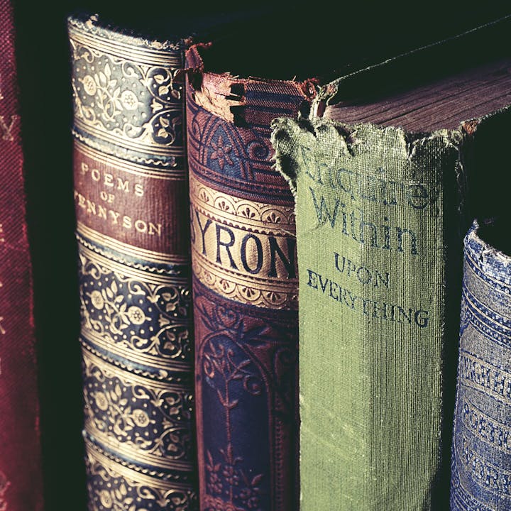 A stack of vintage books with ornate spines, including "Poems of Tennyson" and "Byron."