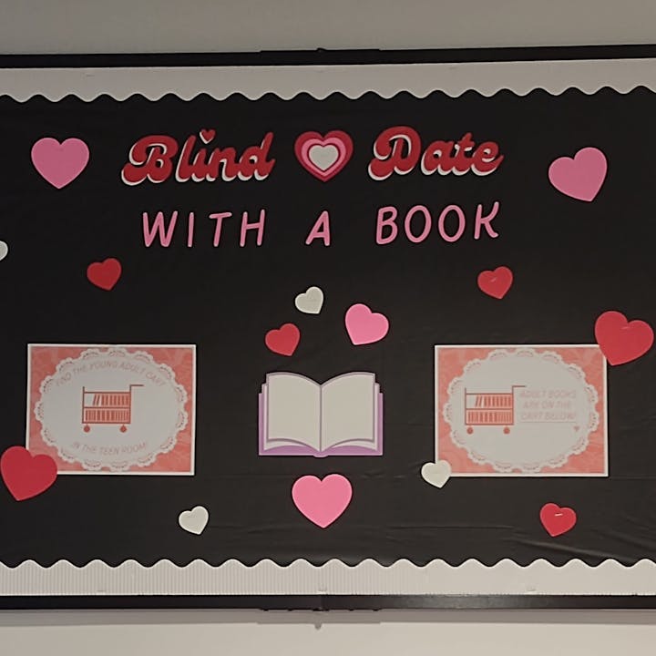 A bulletin board promoting a "Blind Date with a Book" event, featuring hearts and signs for young adult and adult books.