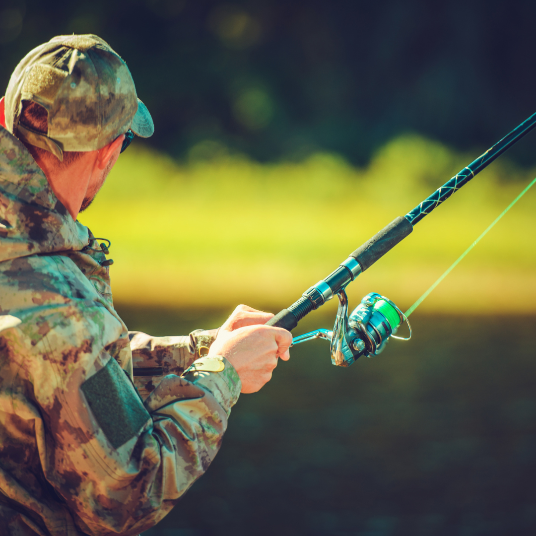 Person in camo gear holding a fishing rod.