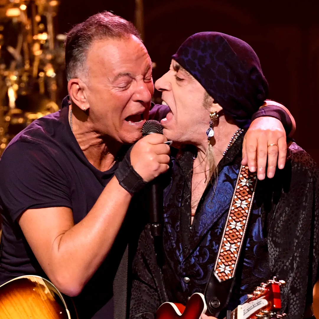 Two musicians sharing a mic, passionately performing on stage.