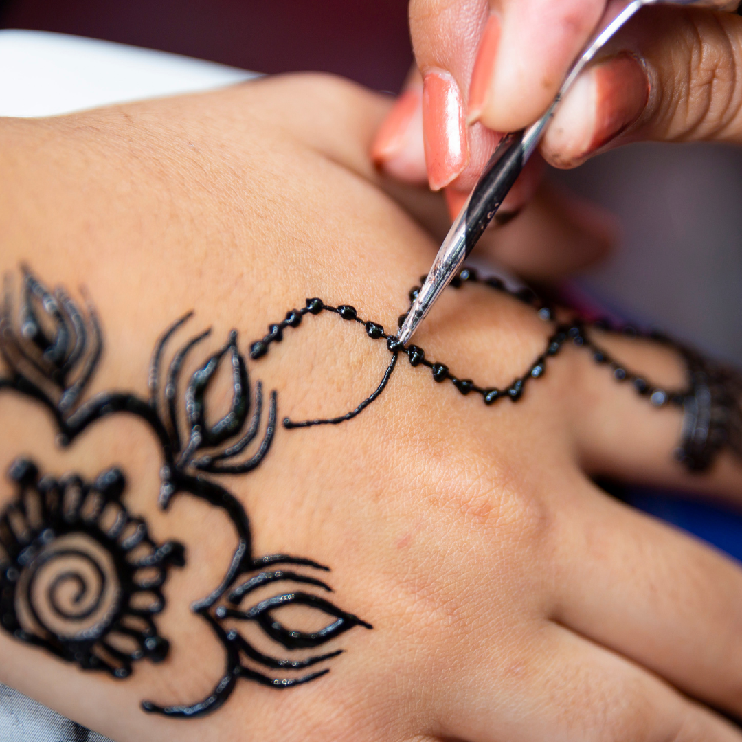 Applying henna design on a hand.