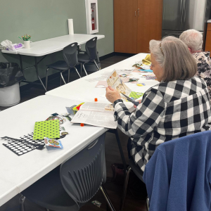 Elderly individuals engaged in a craft activity at a table with various materials.