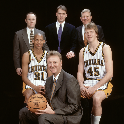 A group photo of six individuals, including basketball players and coaches, posed together, highlighting a team spirit.
