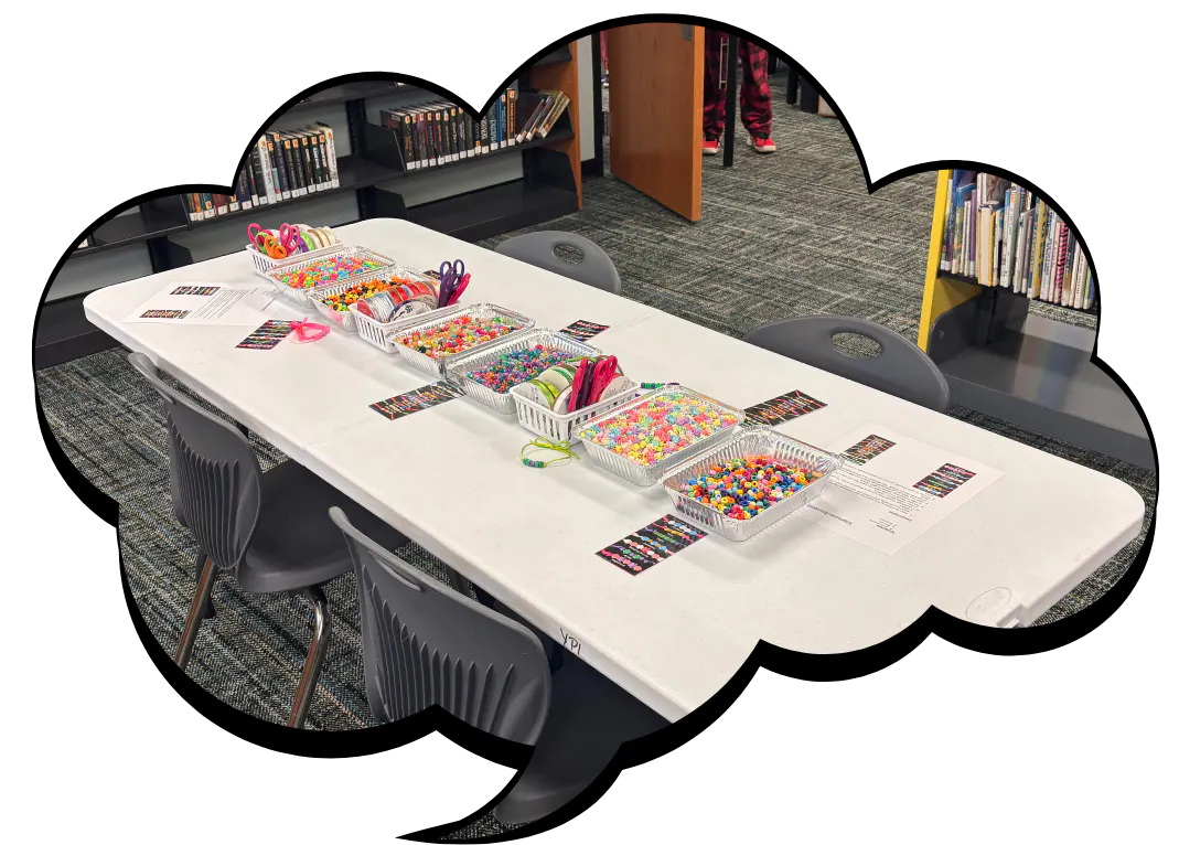 A table in a library with colorful craft supplies like beads and scissors, ready for a creative activity.