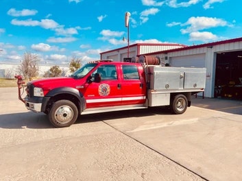 Red fire service truck in front of a building with clear skies.