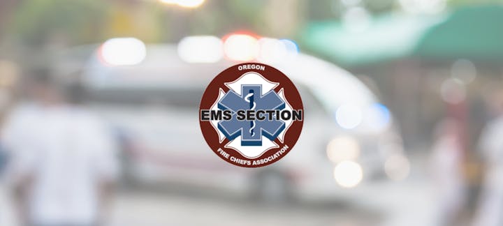 A logo for "EMS SECTION Oregon Fire Chiefs Association" overlaid on a blurred background with indistinct figures and lights.
