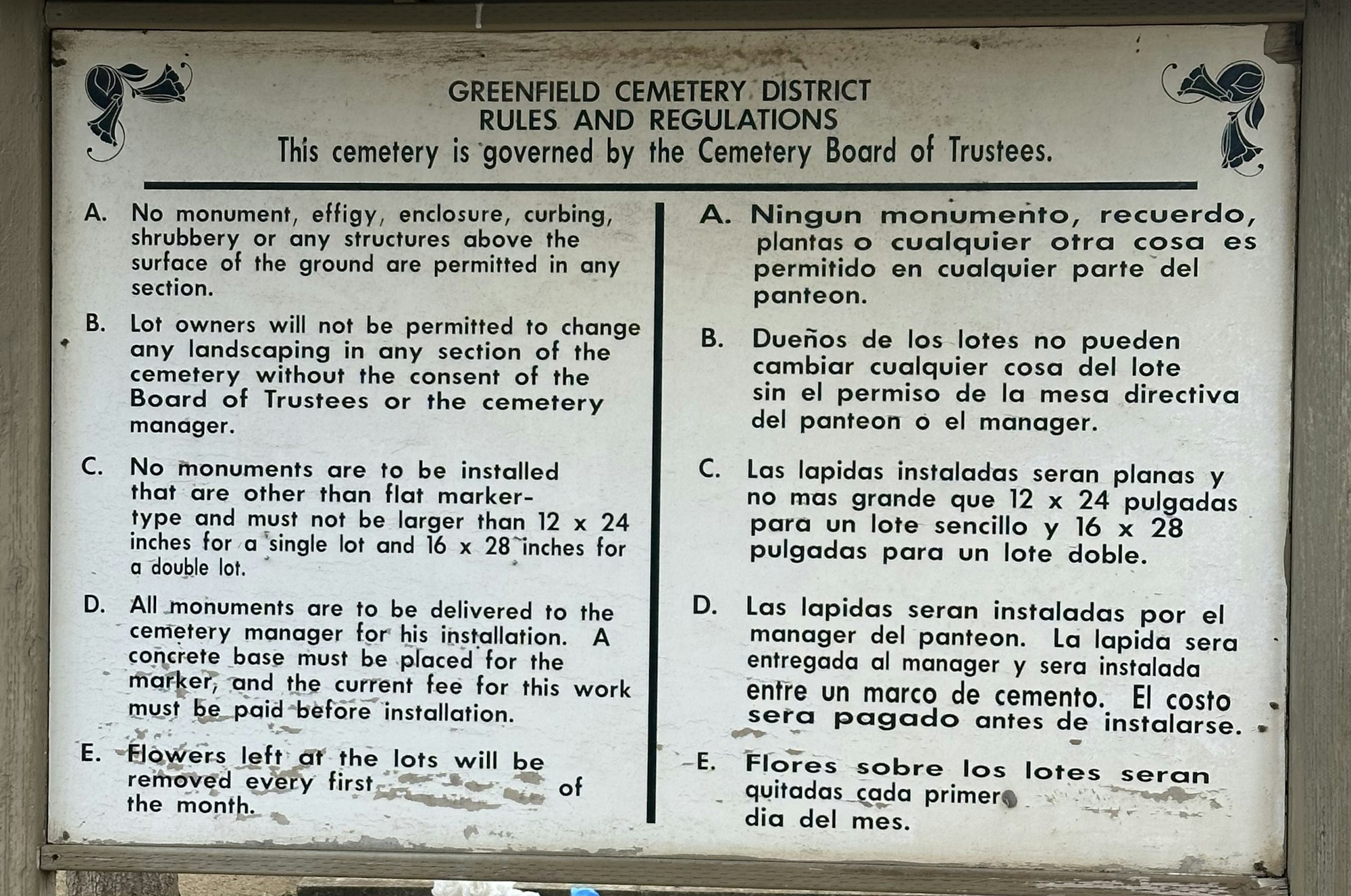 Sign with rules and regulations for a cemetery, including monument restrictions and maintenance guidelines, in English and Spanish.