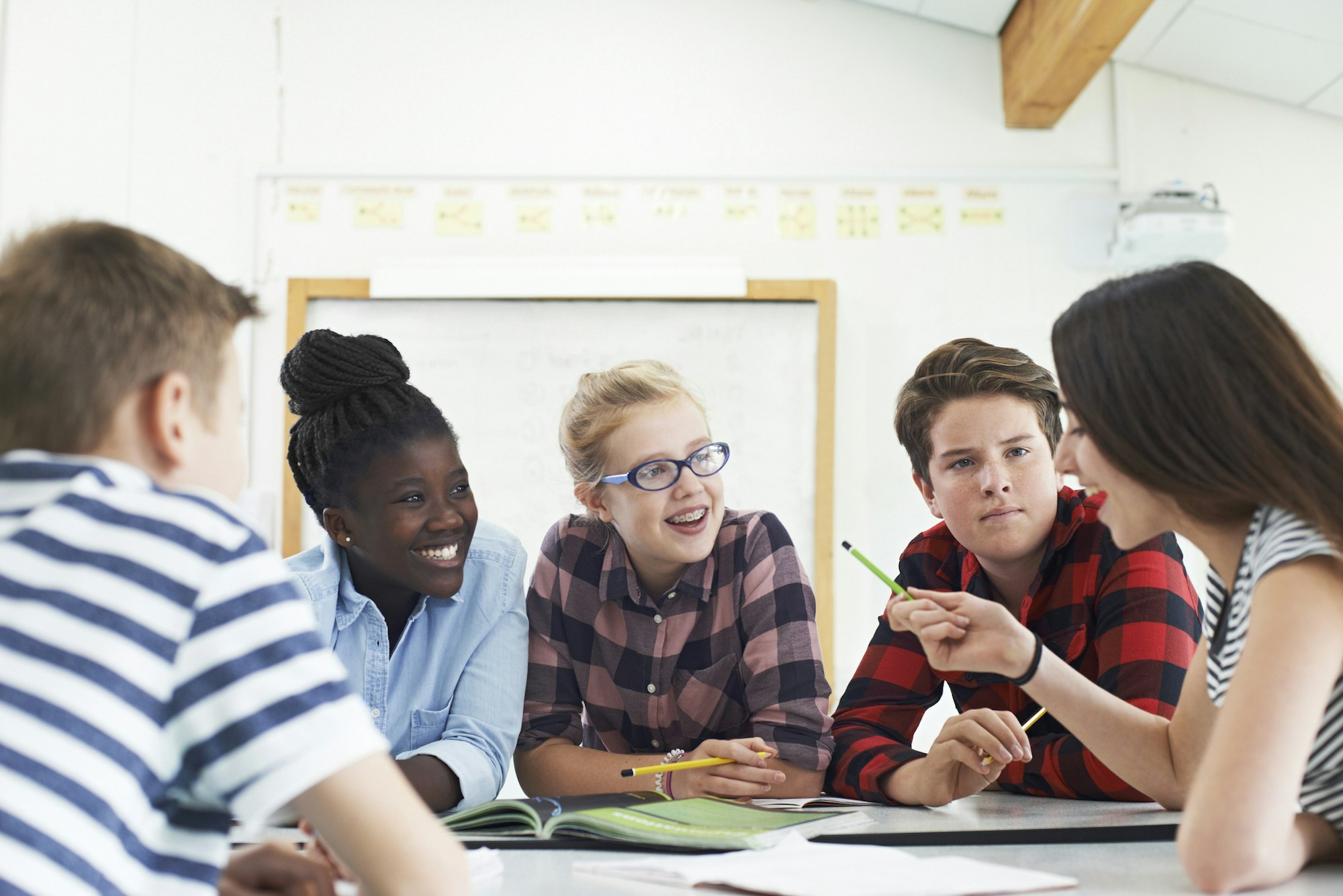 A group of students engaged in a discussion around a table in a classroom setting.