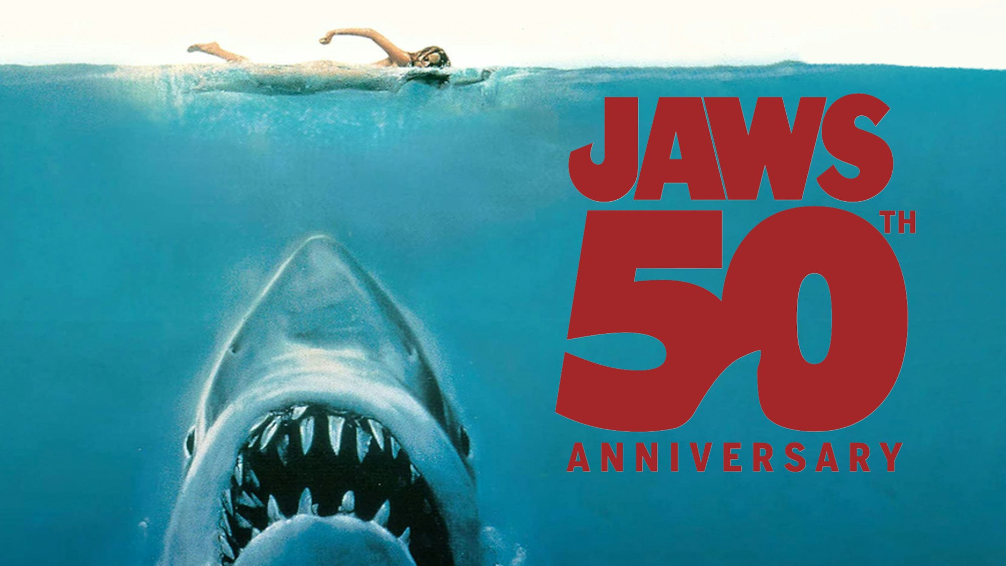 A swimmer above a shark in the ocean, with "JAWS 50th Anniversary" text.