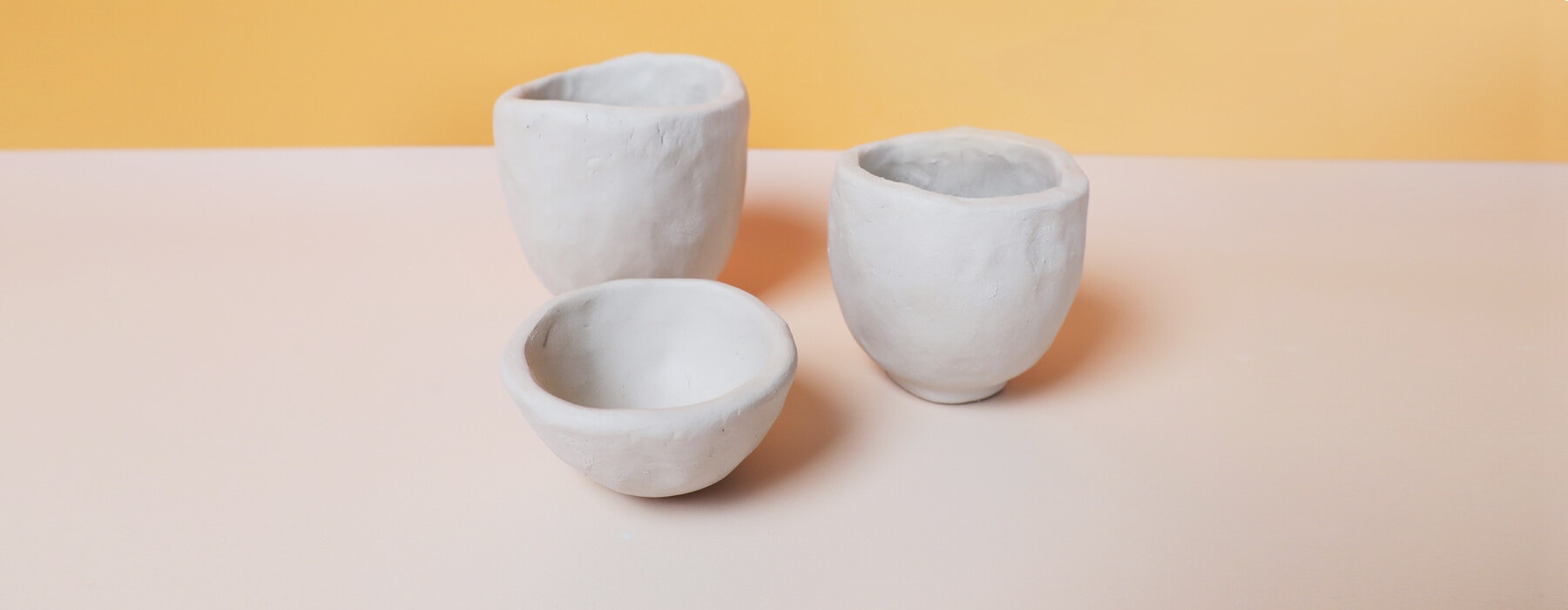 Three handmade clay pots on a two-tone background.