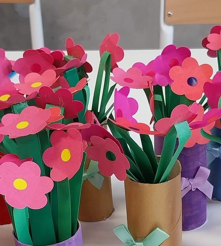 Colorful paper flowers made from cardboard tubes and paper, tied with bows.