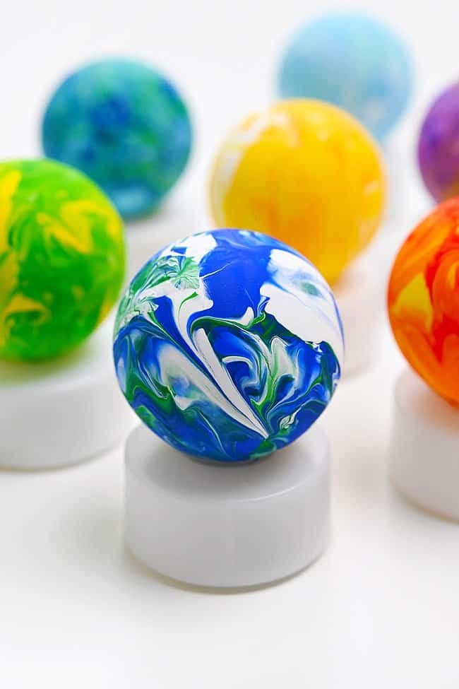 Colorful marbled balls on white stands, featuring blue, green, yellow, and orange swirls.
