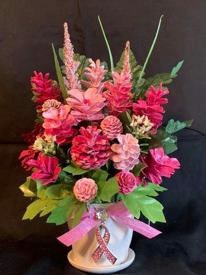 Pink and red flower arrangement in a white vase with a pink ribbon decoration.