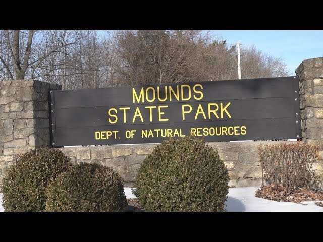 The image shows a stone sign for Mounds State Park, noting its affiliation with the Department of Natural Resources.