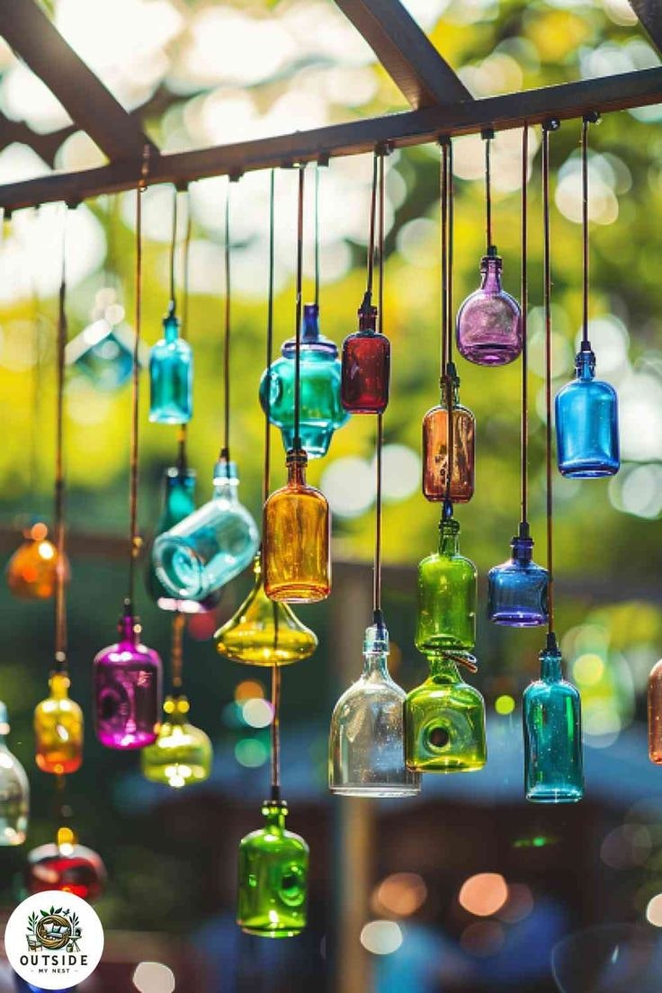 Colorful glass bottles hanging from strings with a blurred nature background.