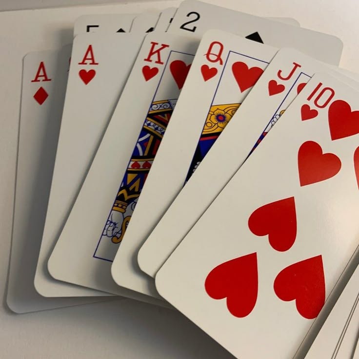 A fan of playing cards showing a royal flush in hearts: 10, J, Q, K, A, plus other cards.