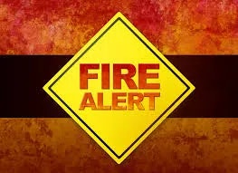Yellow sign with "FIRE ALERT" text in red, on a background with red and orange hues.