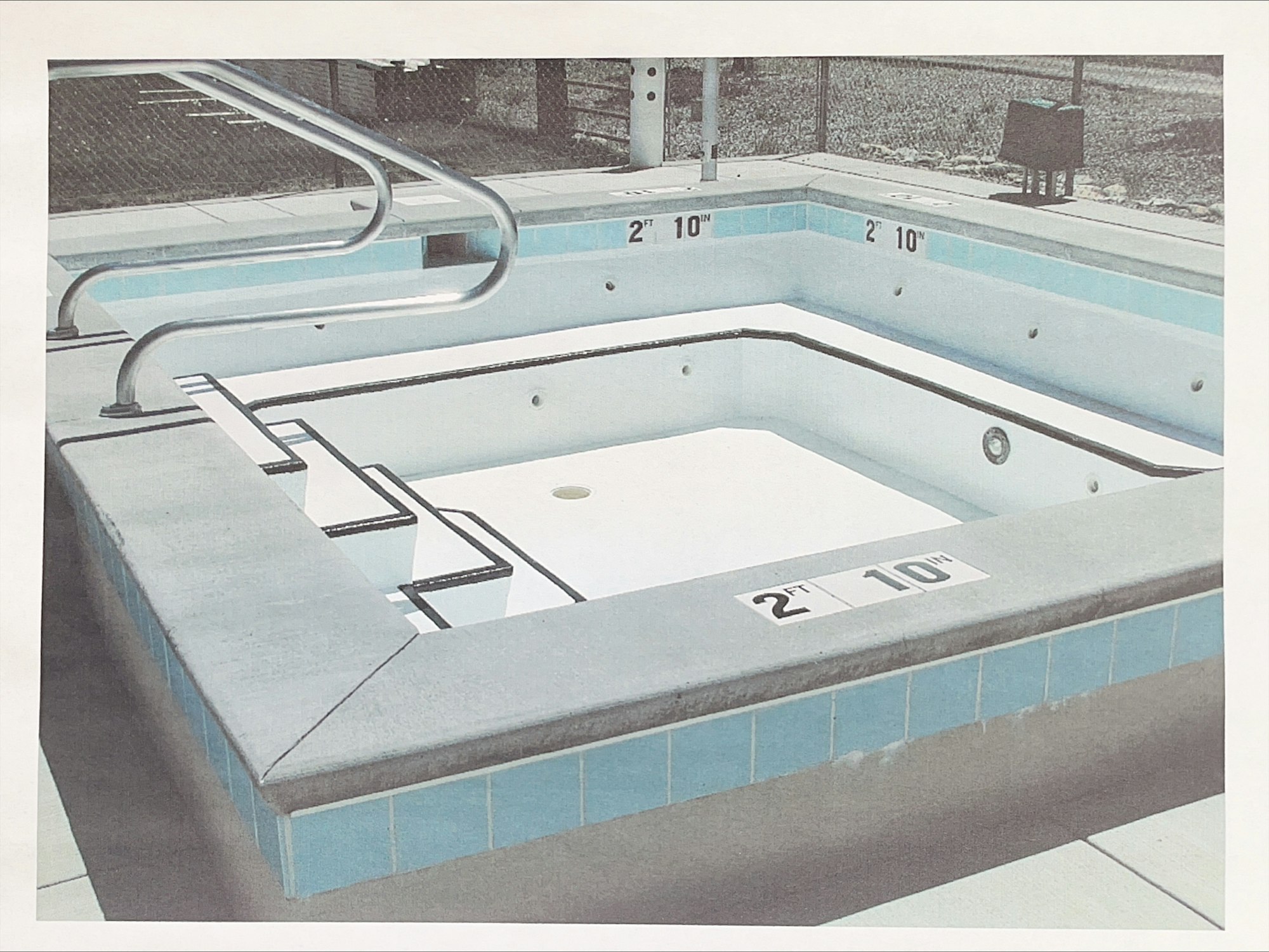 Empty swimming pool with a slide, depth markers showing 2 ft 10 in.