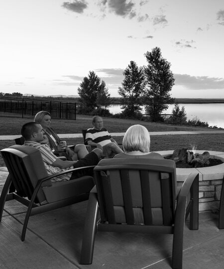 People relaxing by a fire pit near a lake at twilight.