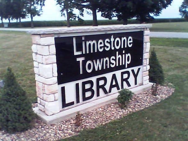 A sign for the Limestone Township Library, featuring the name prominently displayed with decorative landscaping.