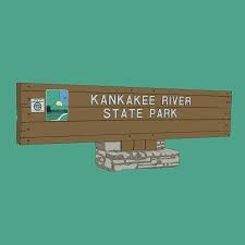 A wooden sign for Kankakee River State Park with a small image and icon, set against a solid green background.