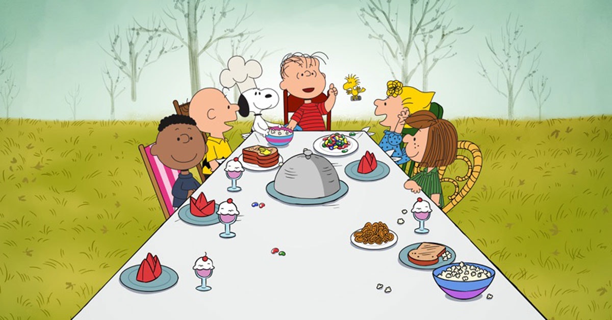 Animated characters having a meal at a table outdoors, with various foods like ice cream sundaes, pretzels, and popcorn.