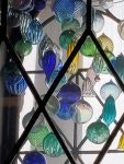 Stained glass window with colorful round glass pieces in blue, green, yellow, and clear shades.