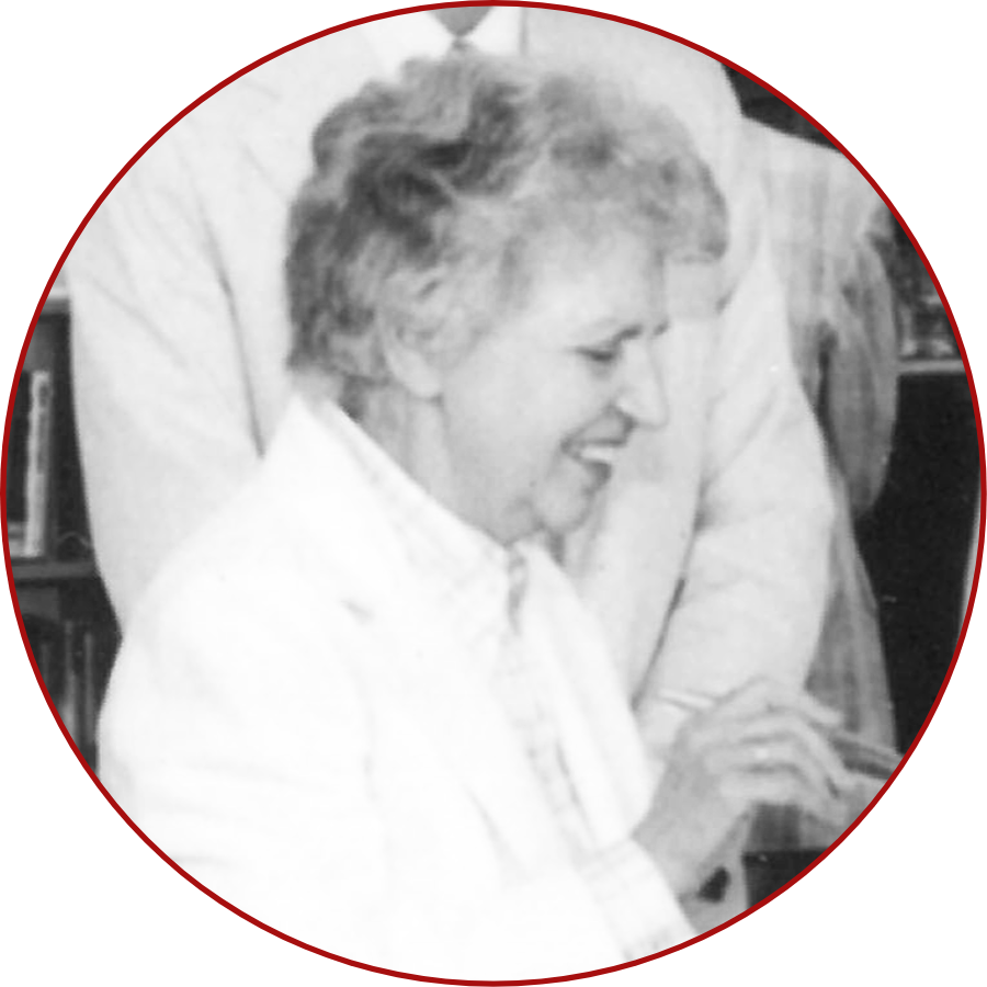 A black and white photo of a smiling person in profile, wearing a light-colored blazer.