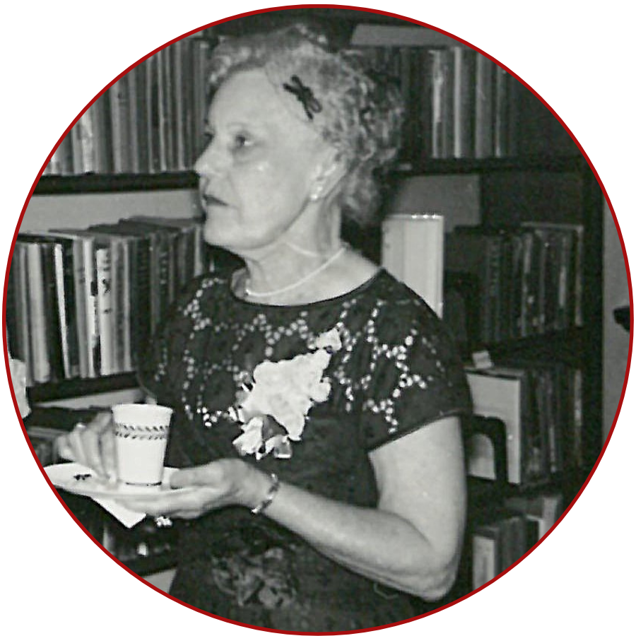 A Photo of Nina Dulin Russell, an elderly woman holding a teacup in the library's reference room with bookshelves in the background.