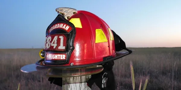 Fire helmet on a fence post with a sunset in the background