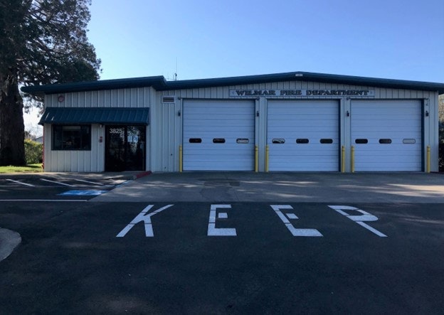A fire station with three garage doors and a "KEEP CLEAR" marking on the pavement.