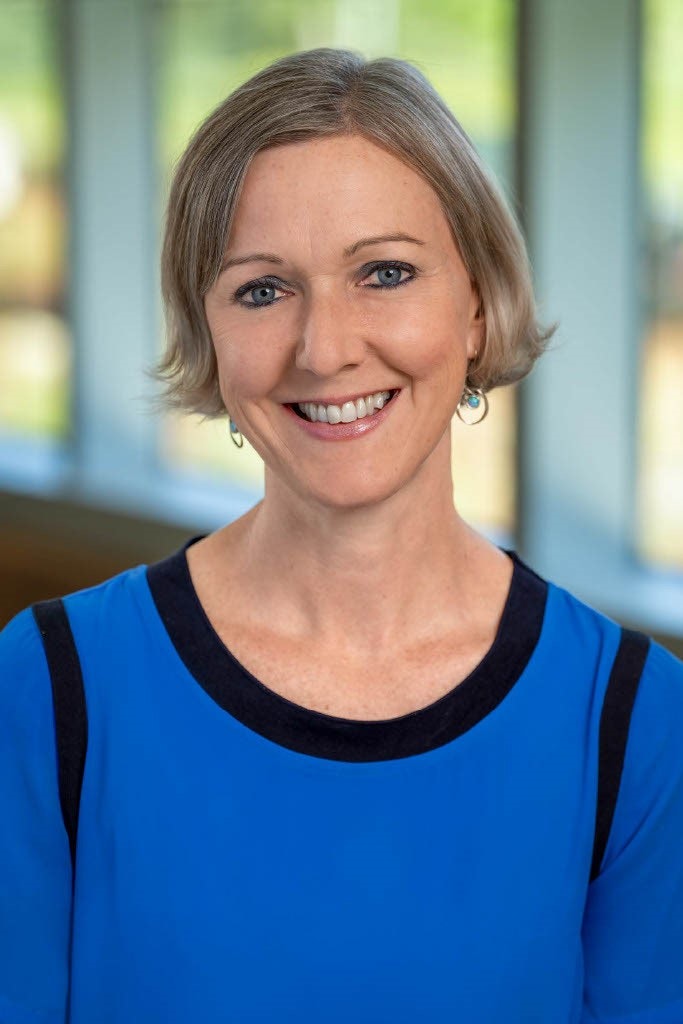 Kirsty Jenkinson with short hair smiling, wearing a blue top with a blurred background.