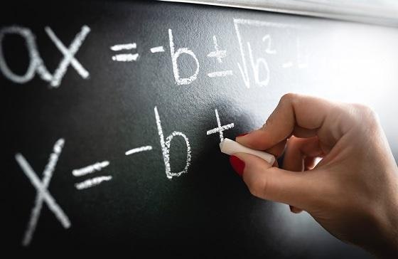 Hand writing math equations on chalk board