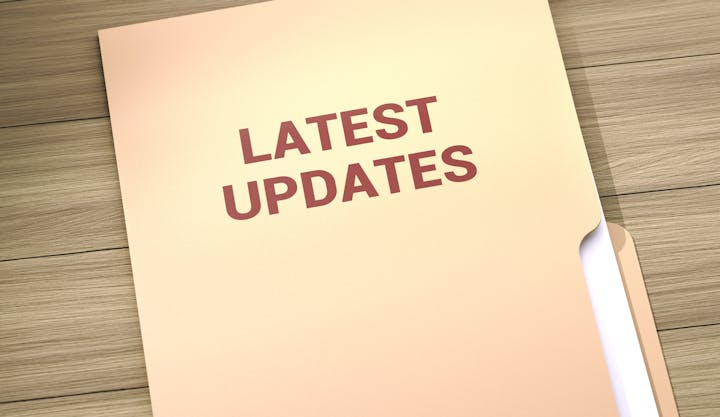 The image shows a folder labeled "LATEST UPDATES" resting on a wooden surface.