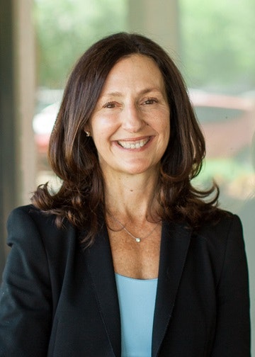 A smiling woman with long hair in professional attire.