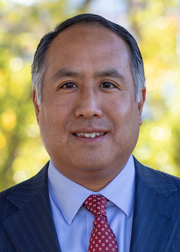 Deputy CIO Scott Chan smiles. He is wearing a blue blazer and red tie.