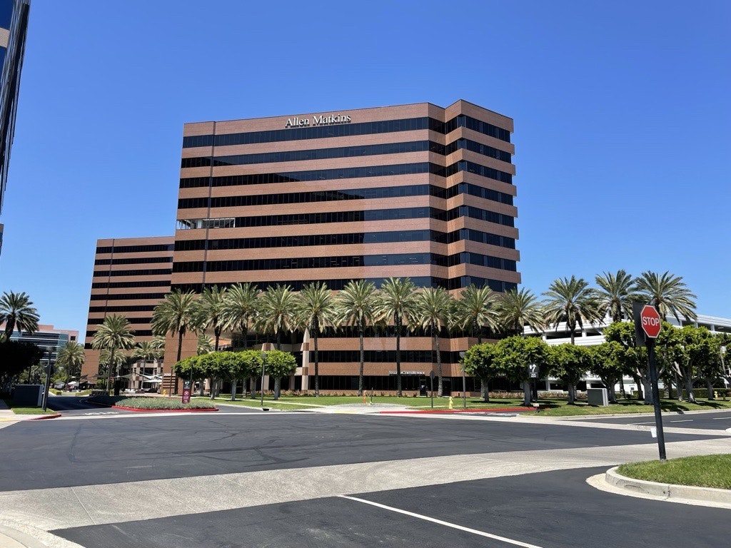 Modern office building with palm trees, blue sky, and a stop sign.