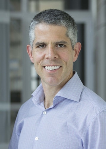 David Lamoureux wearing a light purple shirt, set against a blurred background.