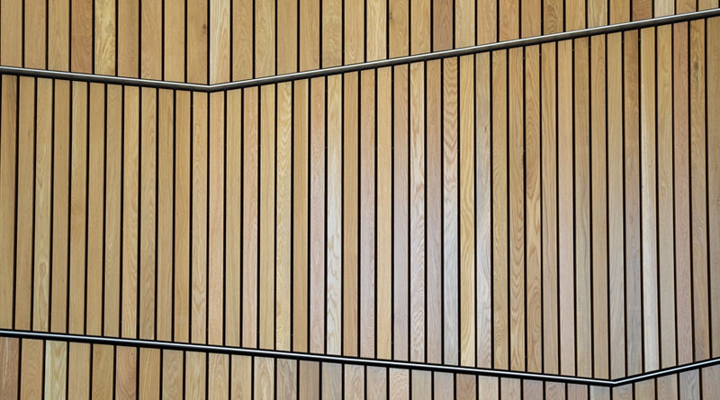 Wooden slatted wall with diagonal black lines creating a geometric pattern.