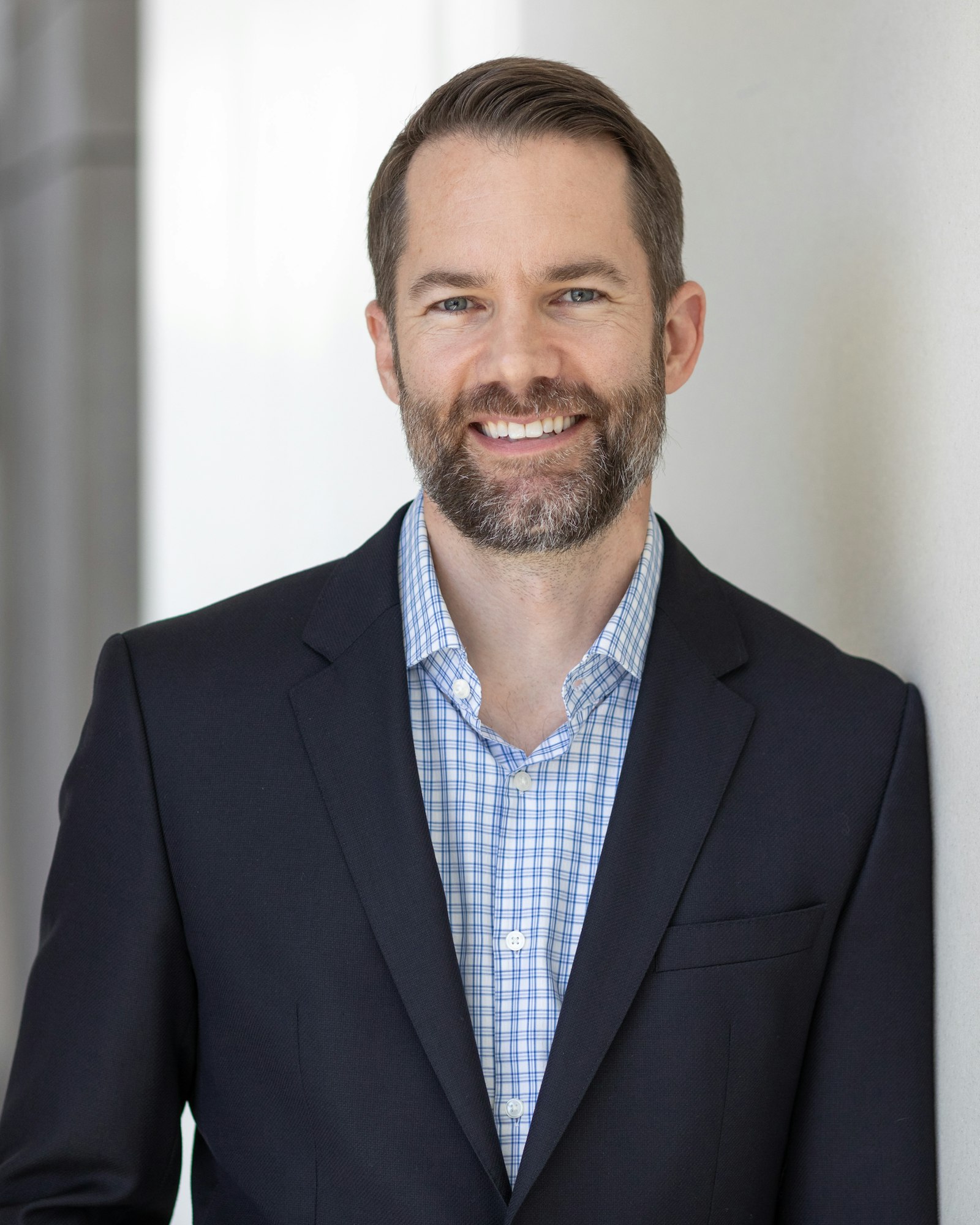 Jeff Zimmer wearing a suit and checked shirt, smiling.