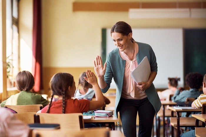 Teacher giving a high-five to a student in a classroom.