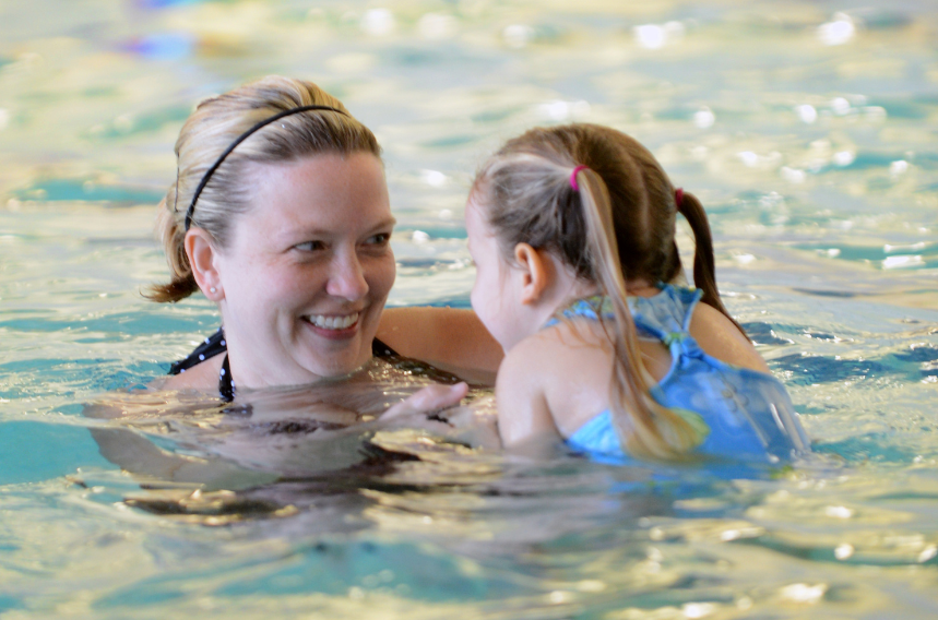 An adult and a child enjoying time together in a swimming pool.