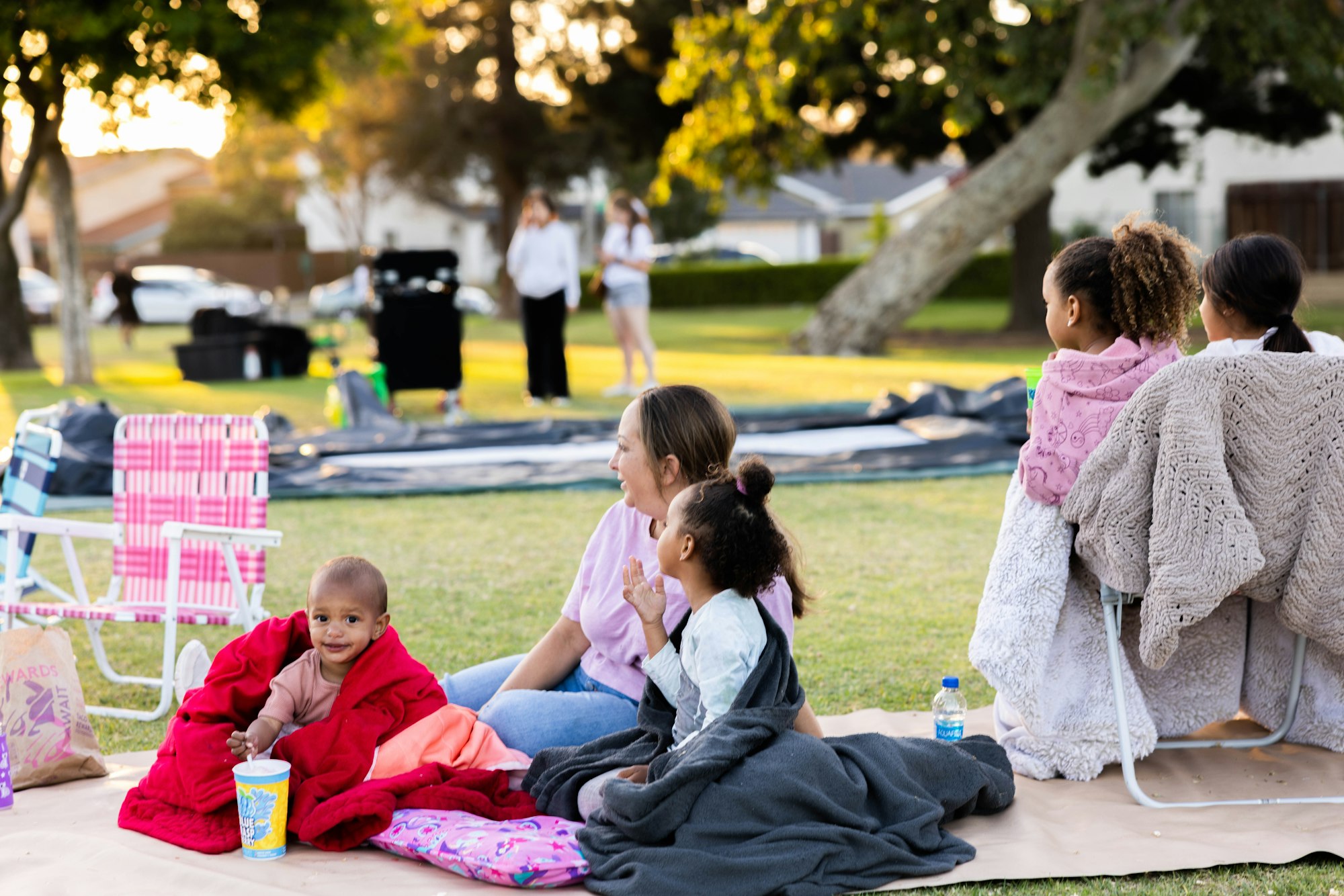 May contain: adult, female, person, woman, cup, child, girl, grass, plant, accessories, bag, handbag, chair, furniture, clothing, footwear, and shoe