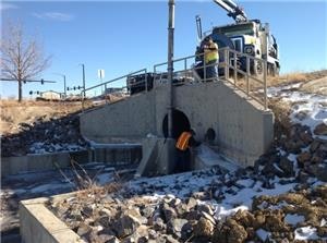 A construction site with machinery, concrete structures, rocks, and some snow.